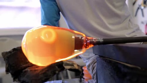 Glass Blower Shaping Molten Glass on Pipe