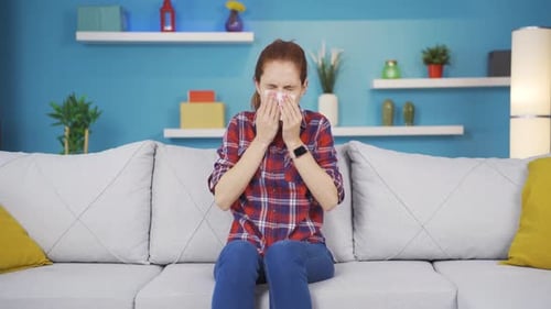 Young woman covering mouth and nose while sneezing.