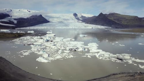 Aerial fly over dramatic icebergs floating in water, Jokulsarlon lake, natural climate snow landscap