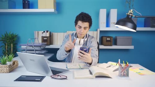 Young Adult Using Smartphone at Desk