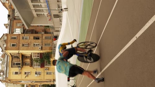 Hombre empujando a un ciclista, ayudando a empezar a andar en bicicleta en el velódromo. Vídeo vertical