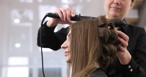 Hairdresser styling woman's hair in beauty salon, closeup