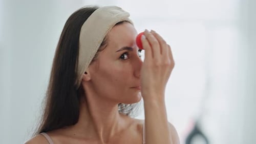 Woman applying makeup using a sponge indoors