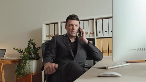 Confident Business Man Making Phone Call in Office