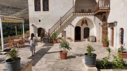 Woman Walking Through Ancient Building's Courtyard