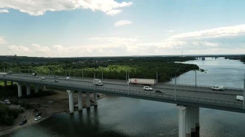 Cars and Trucks Traveling Across Long River Bridge