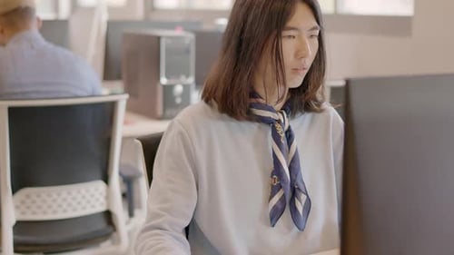 Hombre chino trabajando con una computadora y sonriendo en un coworking
