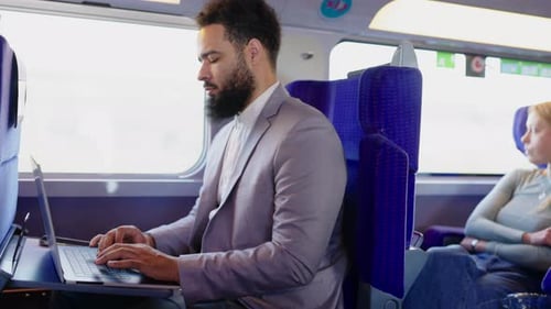 Adult Male Types on Laptop While Riding Train