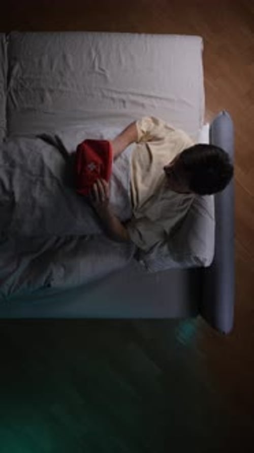 Man Lying in Bed Opens First Aid Kit