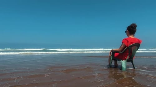 Girl sitting on the beach of Casablanca - filmed from the side, girl centered in the right end of th