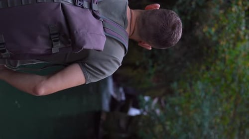 Handsome young man with backpack outdoors on mountain river in forest