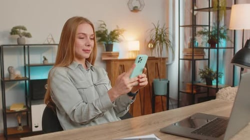 Woman Using Smartphone at Desk in Home Office