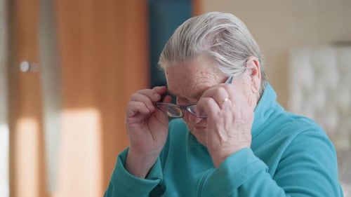 Elderly Woman Putting On Her Eyeglasses Indoors