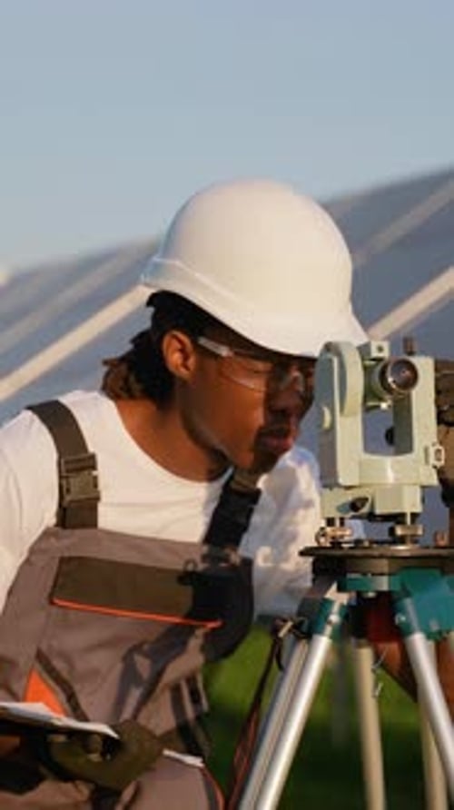 African American Engineer Surveying a Solar Panel Farm