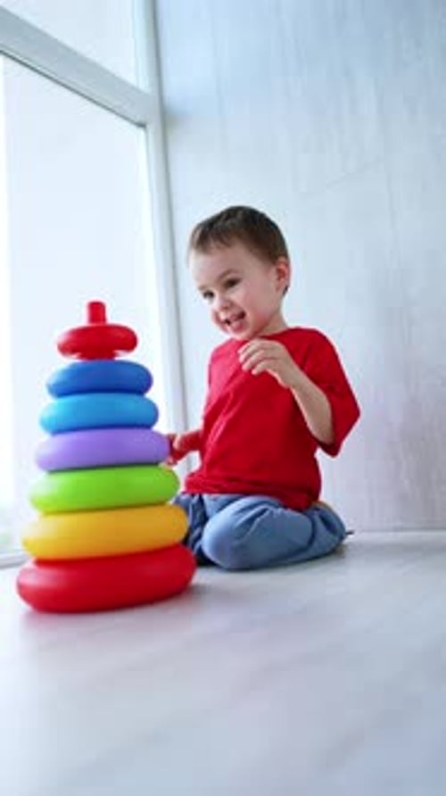 Adorable bebé feliz juega con la pirámide sentado en el suelo.