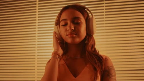 Woman Listens to Music with Headphones in Warm Light
