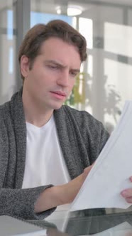 Focused Man Reviewing Documents at Modern Office Desk