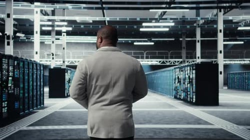 System Administrator Walking in Data Center with Rows of Rackmounts