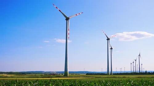 Powerful wind turbines rotate in the wind. Low angle view at the wind mills in the fields.