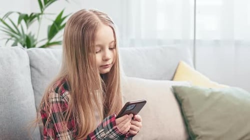 Girl Using Smartphone on Sofa in Bright Home
