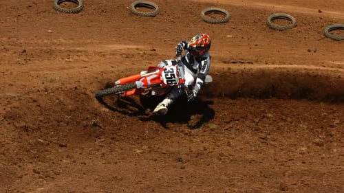 Motocross Rider Leans into a Corner on Dirt Track