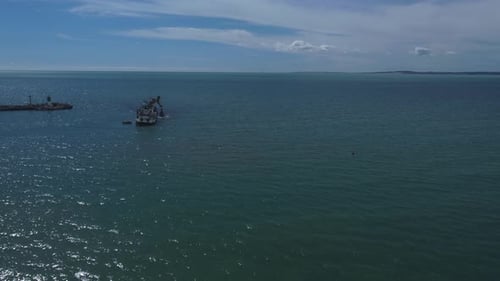 Aerial approach to a boat dredging the entrance of a port
