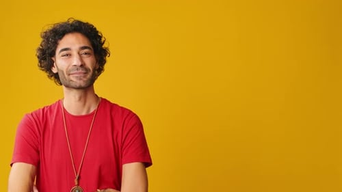 Man looks to side to show space for advertising isolated on yellow background in studio