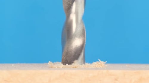 Closeup of a Wood Drill Rotating The Screwdriver Chuck Holds a Sharp Shiny Metal Bit