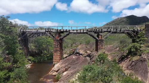 Drohnenaufnahme einer alten Brücke aus der Luft, darunter fließt ein brauner Fluss. 4K-Videos. Annäherungsaufnahme.