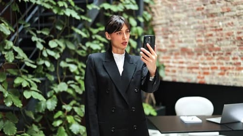 Businesswoman in Modern Office Using Smartphone for Video Call