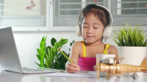 Girl Drawing with Laptop and Headphones at Home