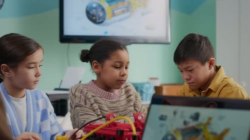 Three Children Collaborate on Robotics Project in Classroom