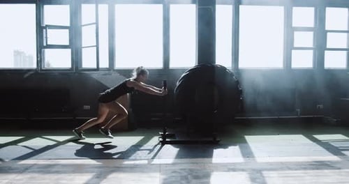 Sliding Side View Young Athletic Caucasian Woman Exercising with Heavy Training Sled in Big