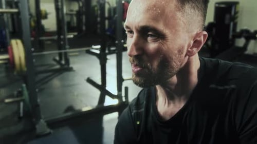 Sweaty Man Doing Seated Single Arm Dumbbell Curls in Gym