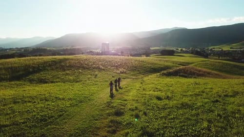 Following a group of mountain bikers riding on the hill above green valley. Friends on bicycles ridi