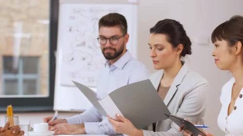 Group of adults in a meeting reviewing documents