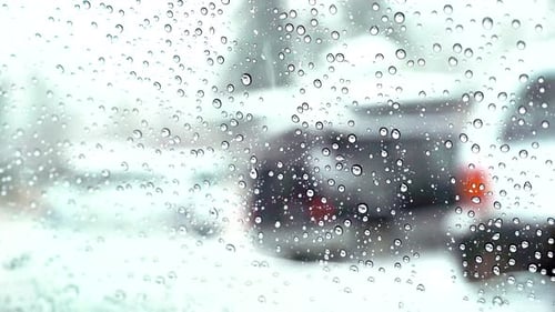 Rain Drops on Window with Blurred City Winter Scene