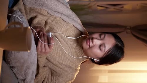 Woman Relaxes Listening to Music Indoors at Night