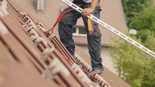 Arbeiter installiert Geländer für Sonnenkollektoren auf dem Dach