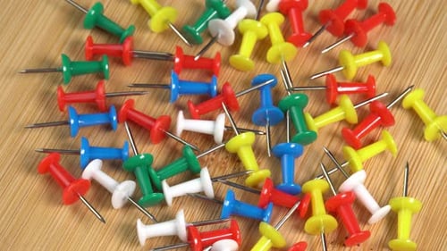 Colorful push pins rotating on the desk. Drawing pins for marking on the map of the Earth or city