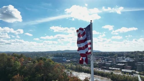 American Flag Waving in the Breeze Over City