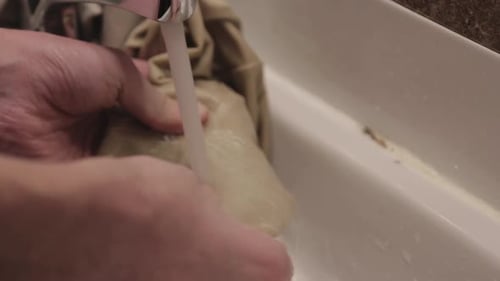 Thoroughly Washing Of A Beige Clothing In A Kitchen Sink. -close up shot
