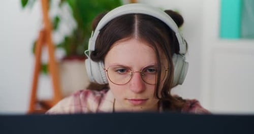 Teen Wearing Headphones Working on Computer