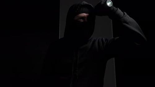 Mysterious Figure with Flashlight in Dark Environment