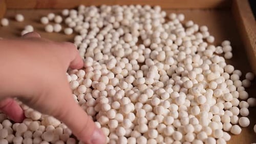 Hand Touches Tapioca Pearls on Wooden Tray