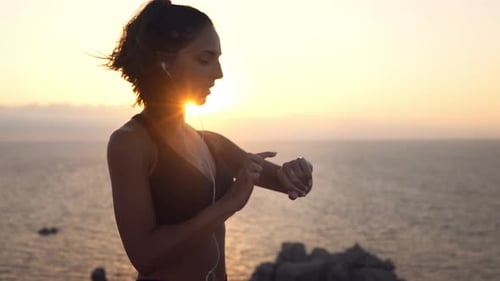 Woman Checks Watch After Workout at Sunrise