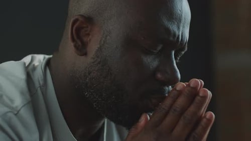 Man Praying with Hands Clasped Together Indoors