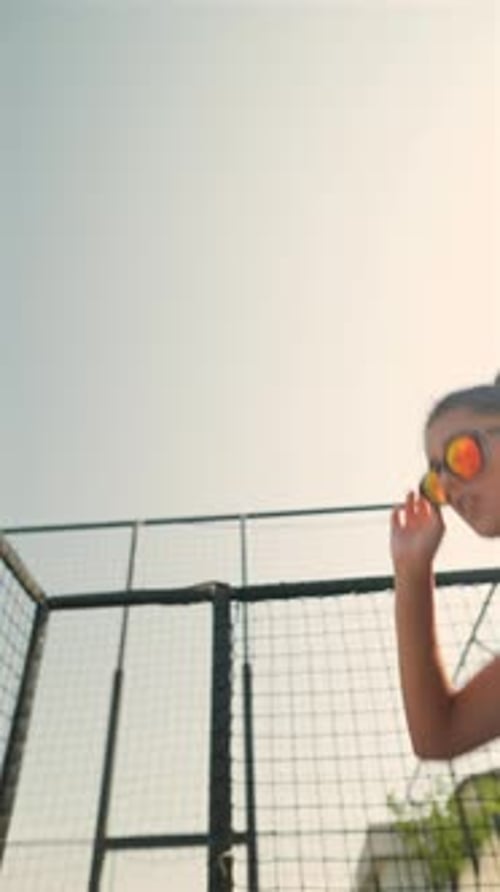The Beach Setting Witnesses a Graceful Young Lady in Glasses and a Bikini Leaping Merrily
