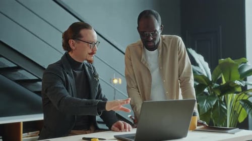 Businessman Discussing Project on Laptop with Colleague in Office