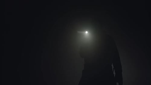 Police Officer Walking in the Dark with Flashlight